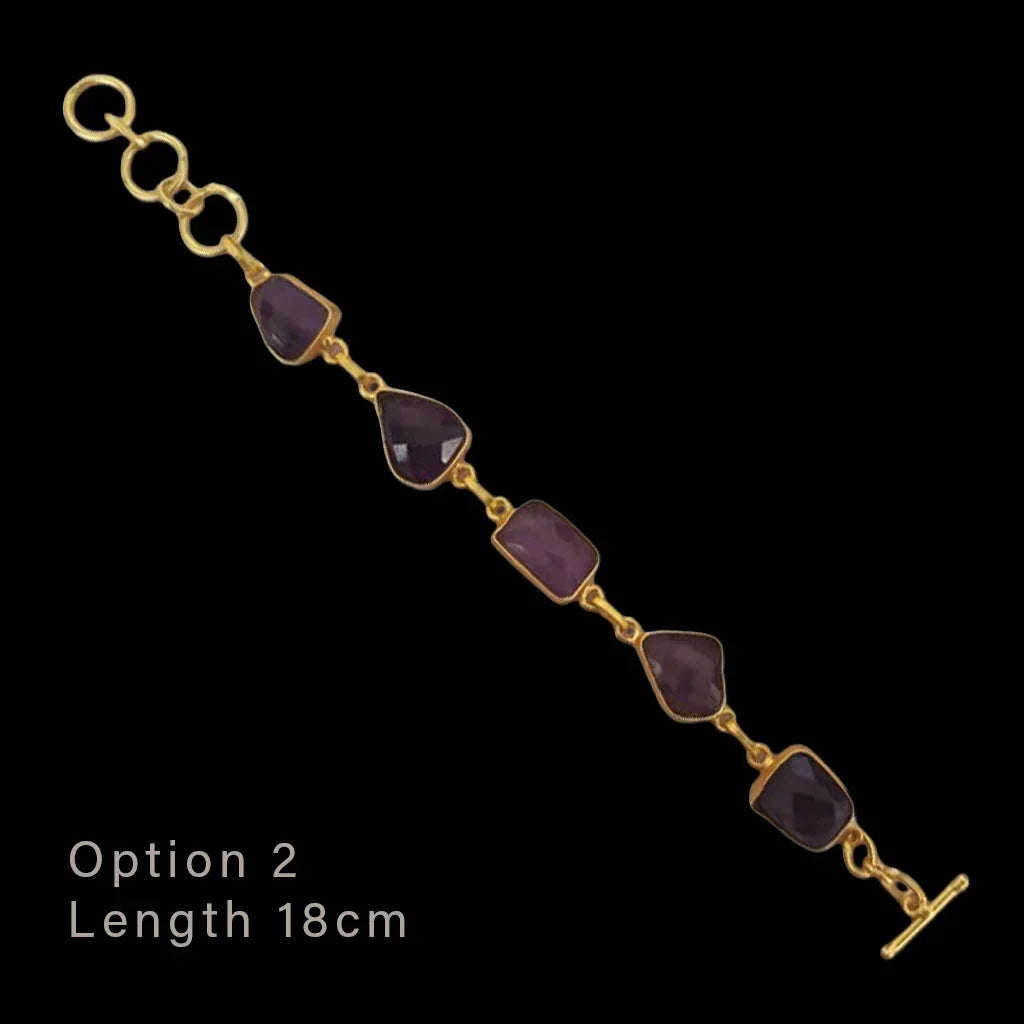 Gold bracelet with purple stones on a black background