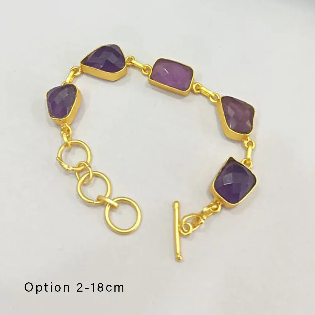 Gold bracelet with purple gemstones on a light gray background