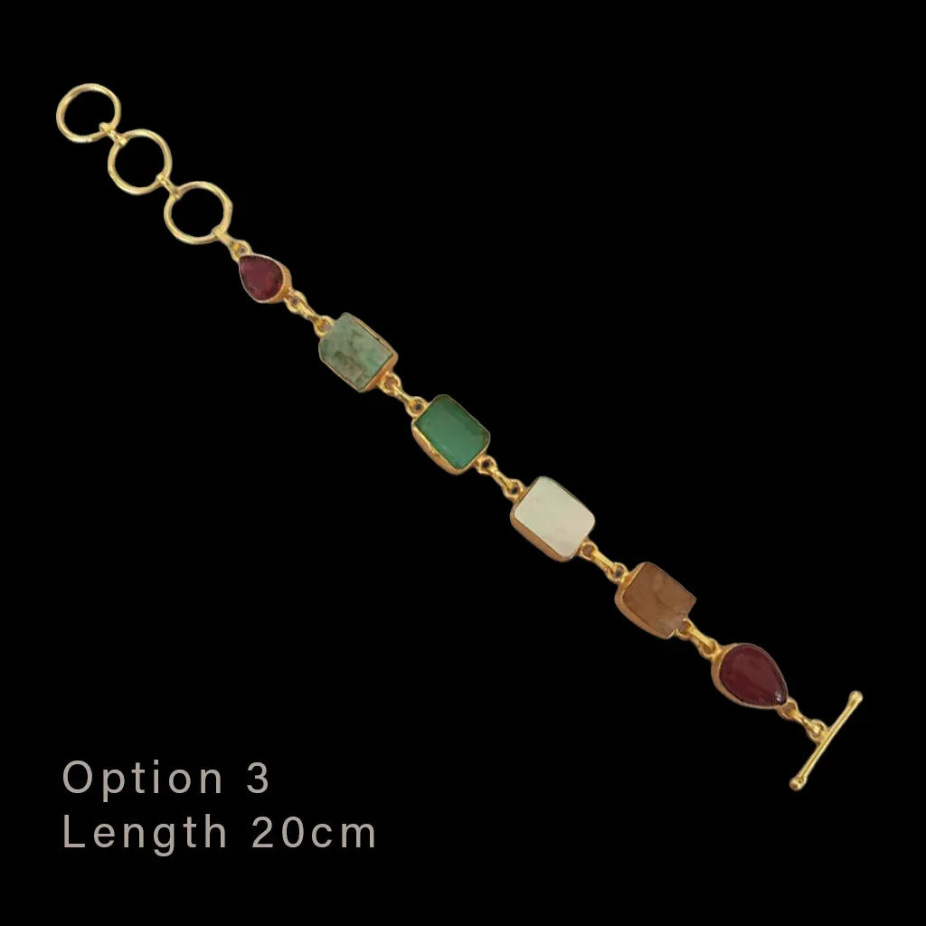Gold bracelet with colored stones on a black background