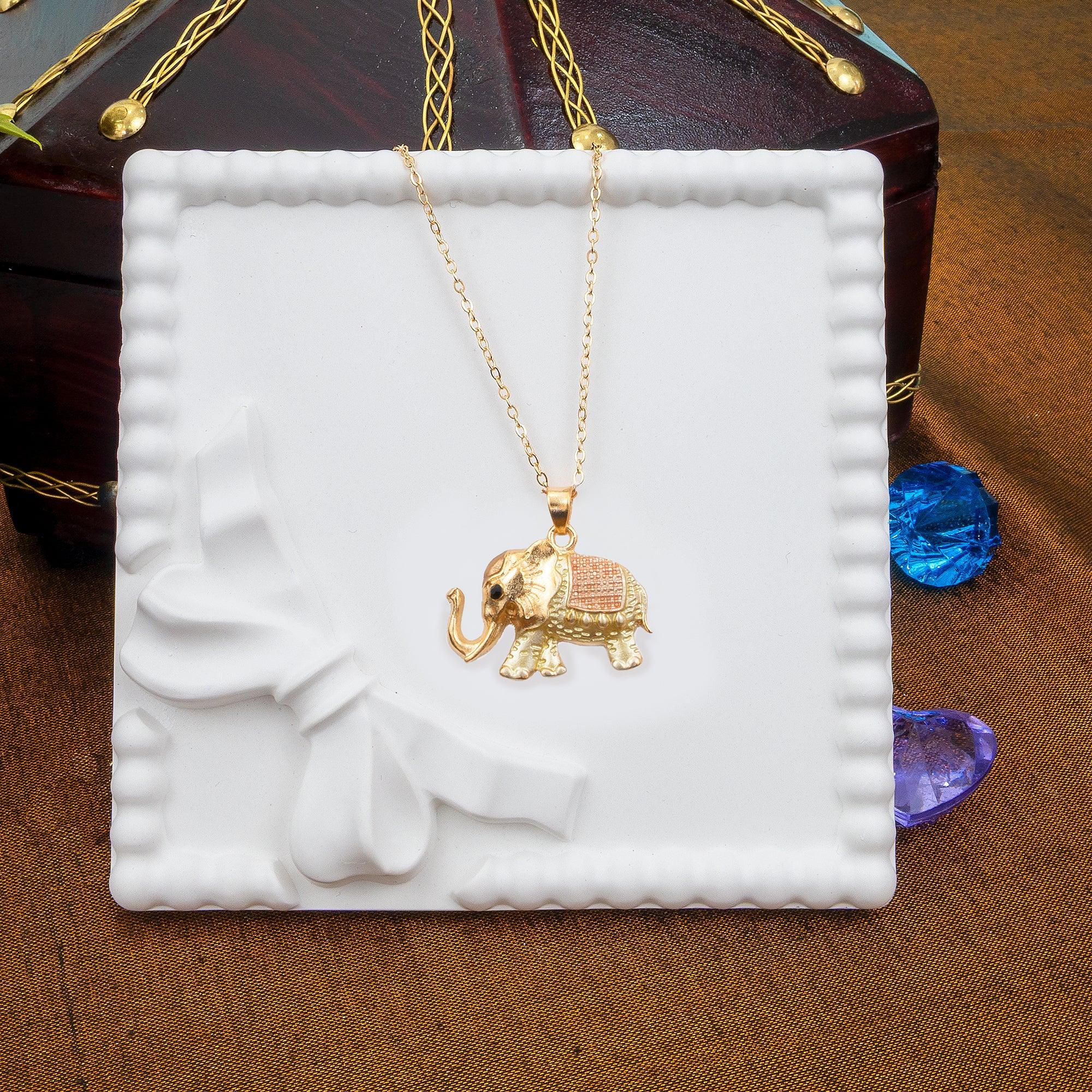 Gold elephant pendant necklace on a white jewelry box with a brown background