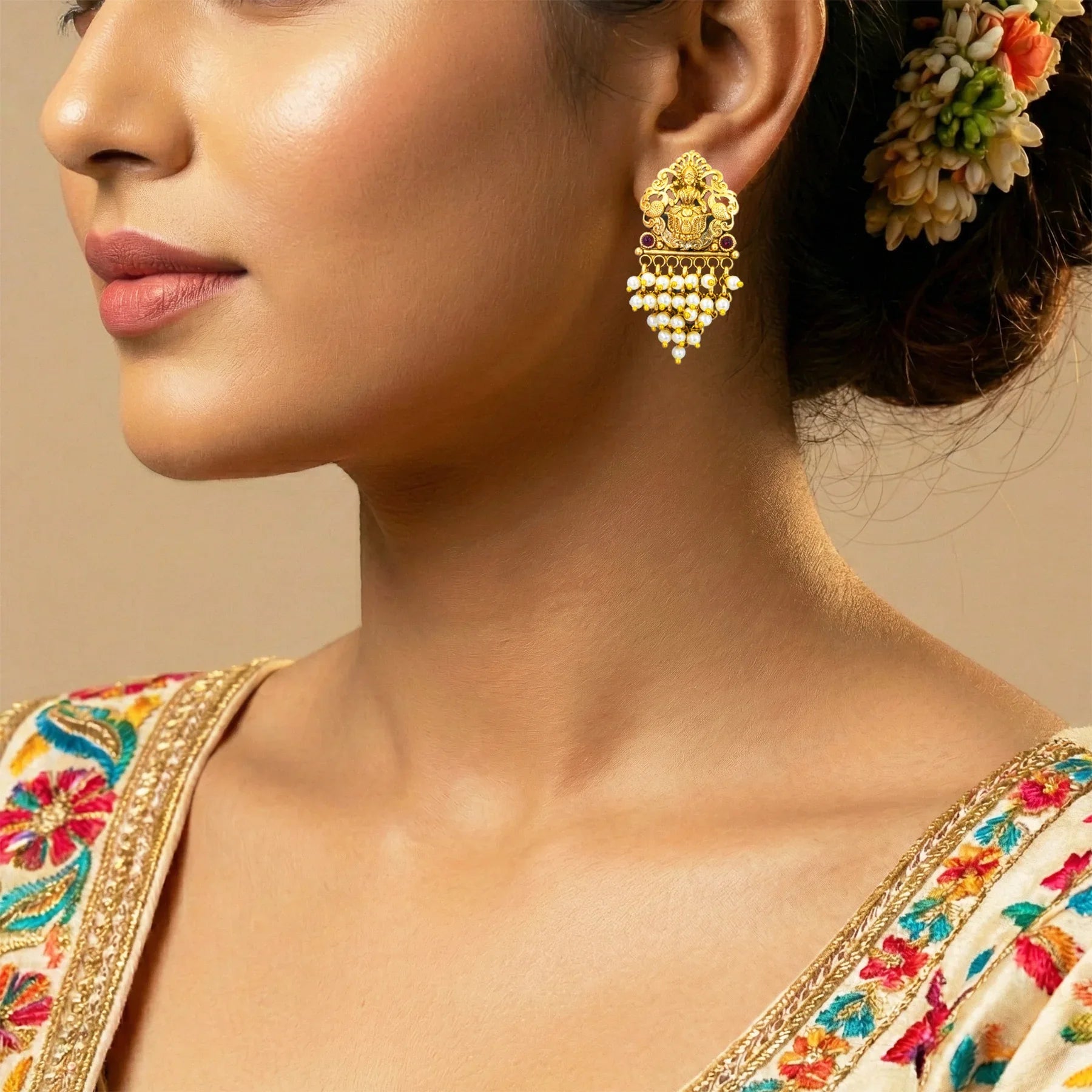Close-up of a woman wearing gold earrings with a neutral background