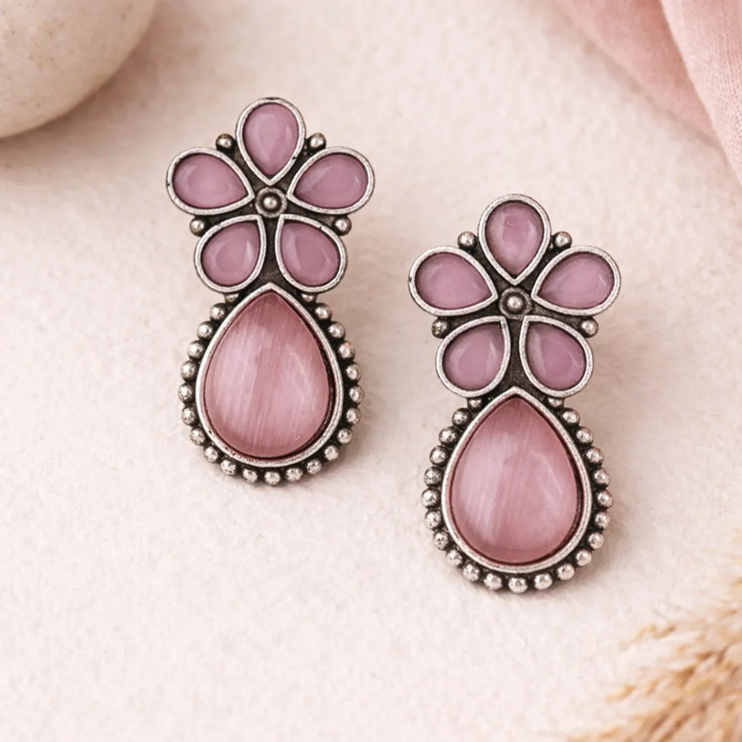 Pink floral earrings on a soft pink background