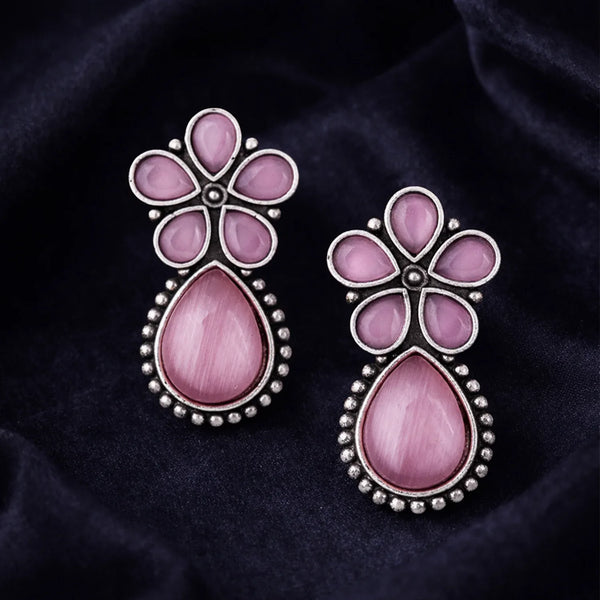 Pair of pink floral earrings on a dark fabric background