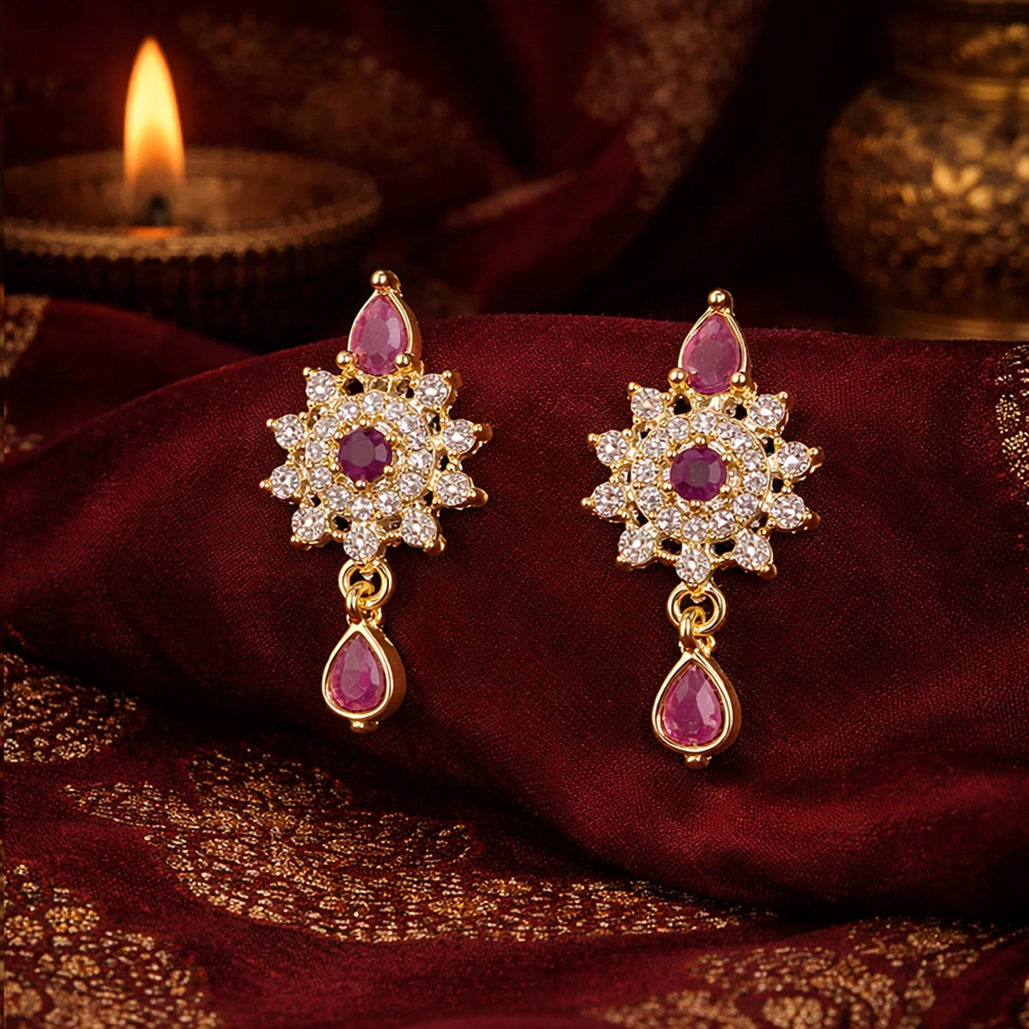 Ornate earrings with gemstones on a maroon fabric background
