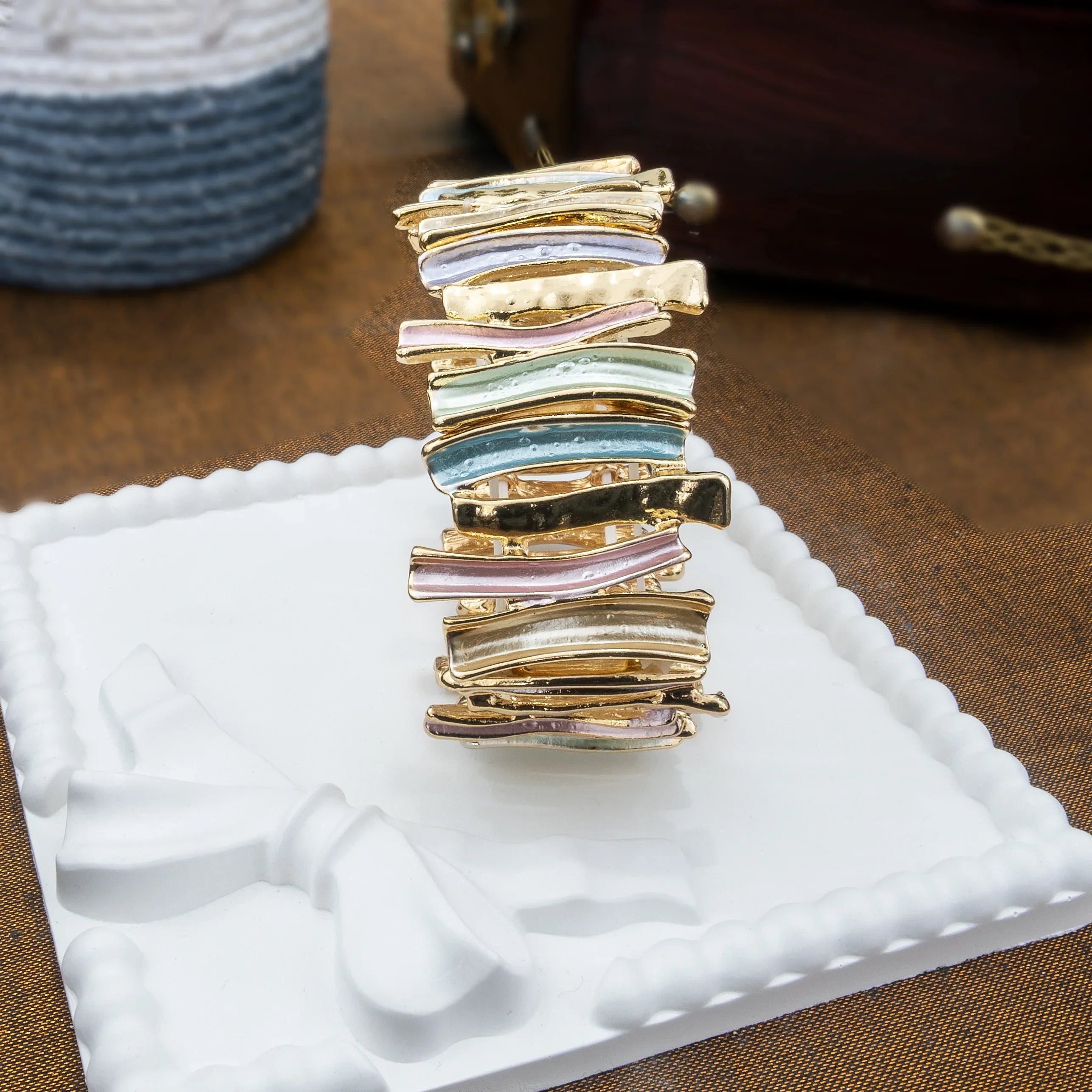 Stack of gold and silver jewelry on a white tray with a blurred background
