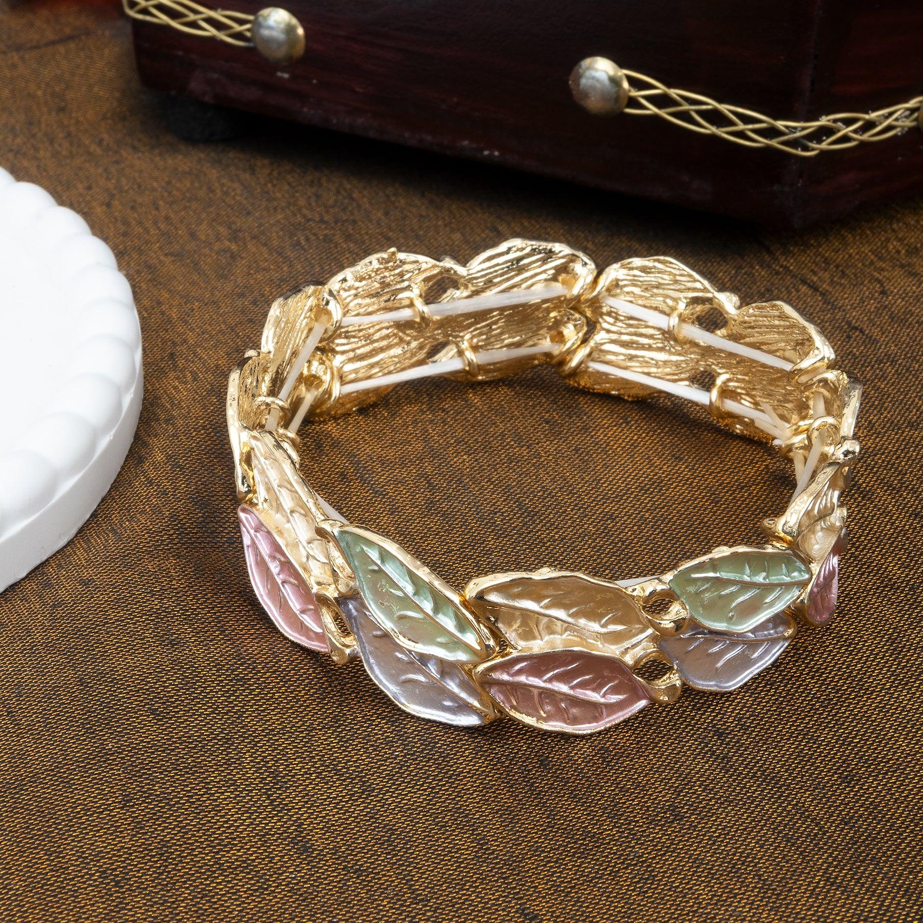 Gold bracelet with leaf-shaped charms on a brown surface