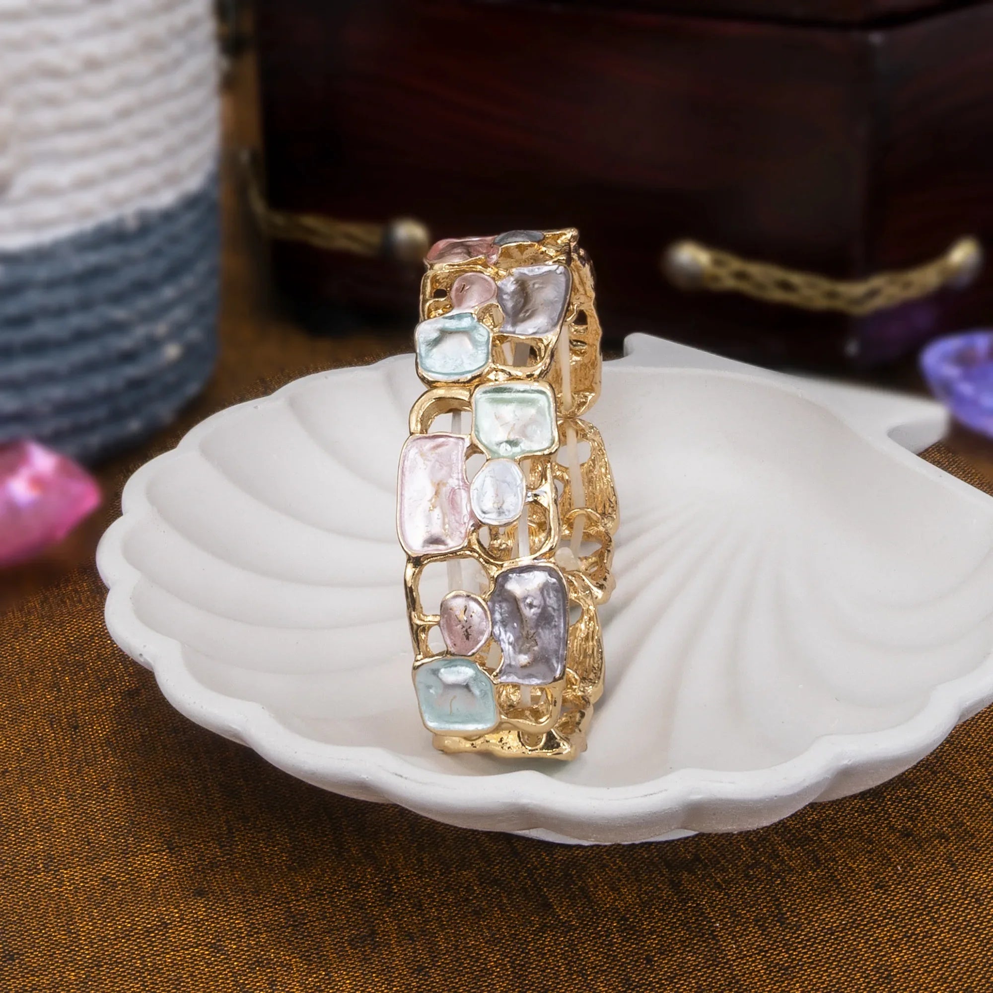 Gold bracelet with multicolored stones on a white shell