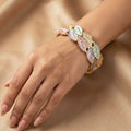 Bracelet with leaf-shaped charms on a hand against a beige background