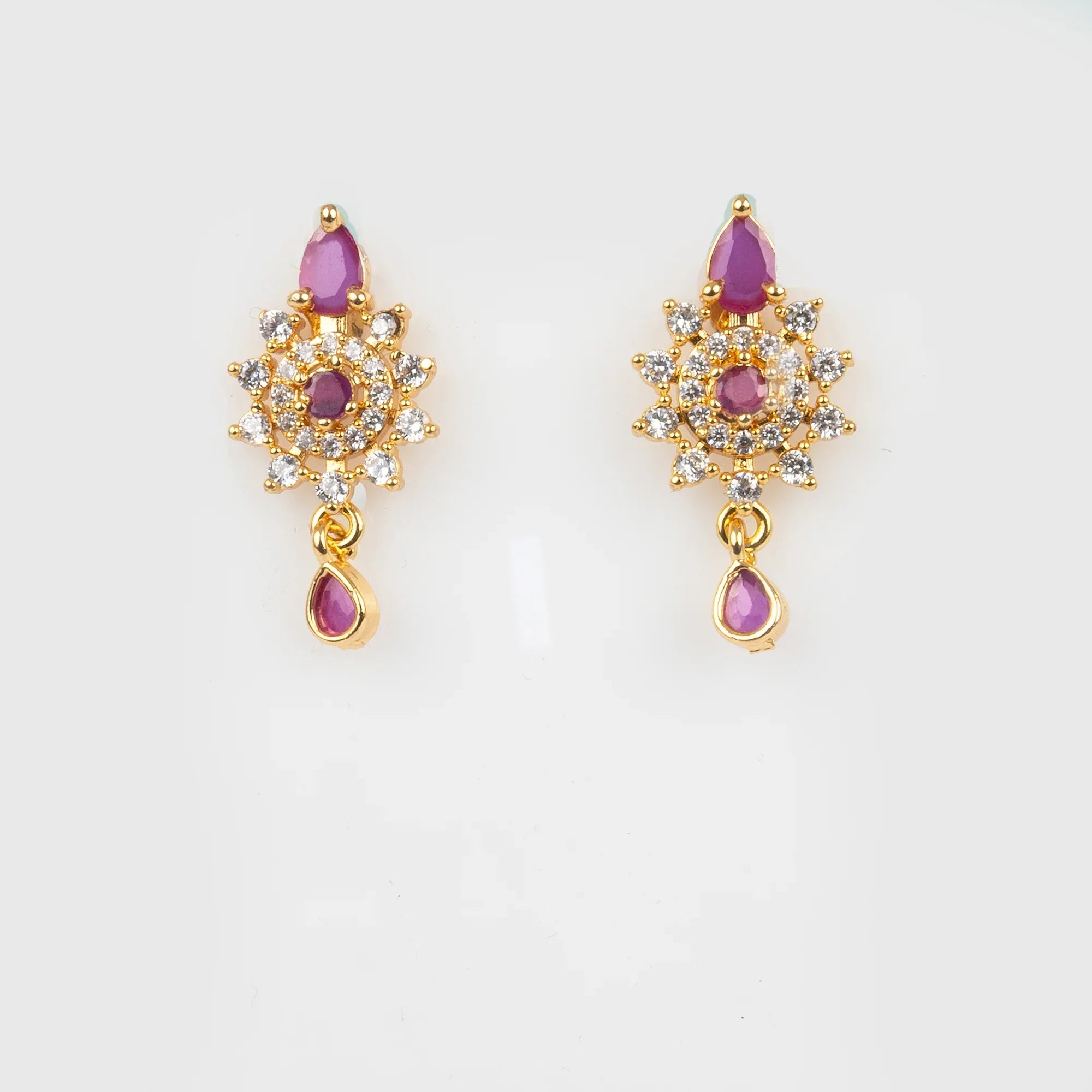 Gold earrings with purple gemstones on a light gray background