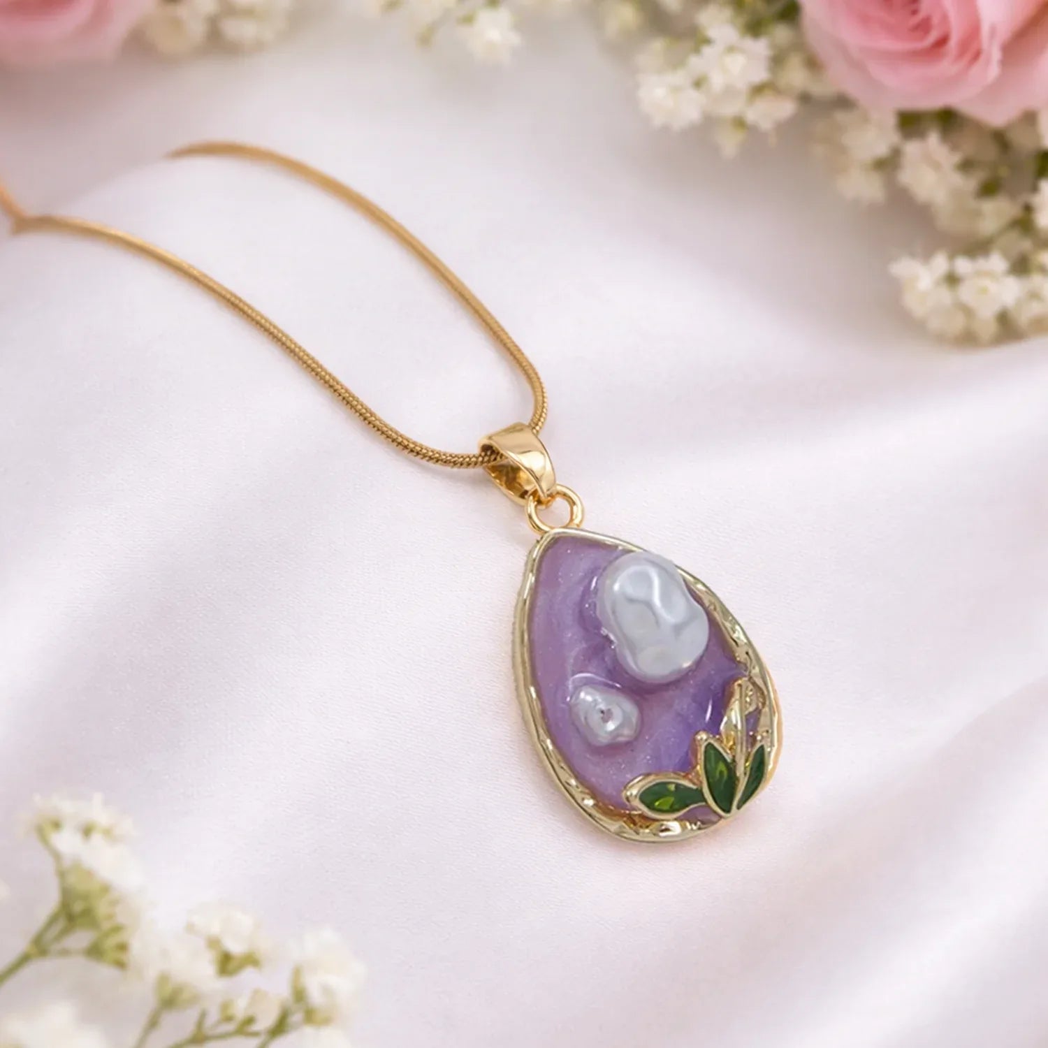 Necklace with a purple teardrop pendant on a white background with flowers.