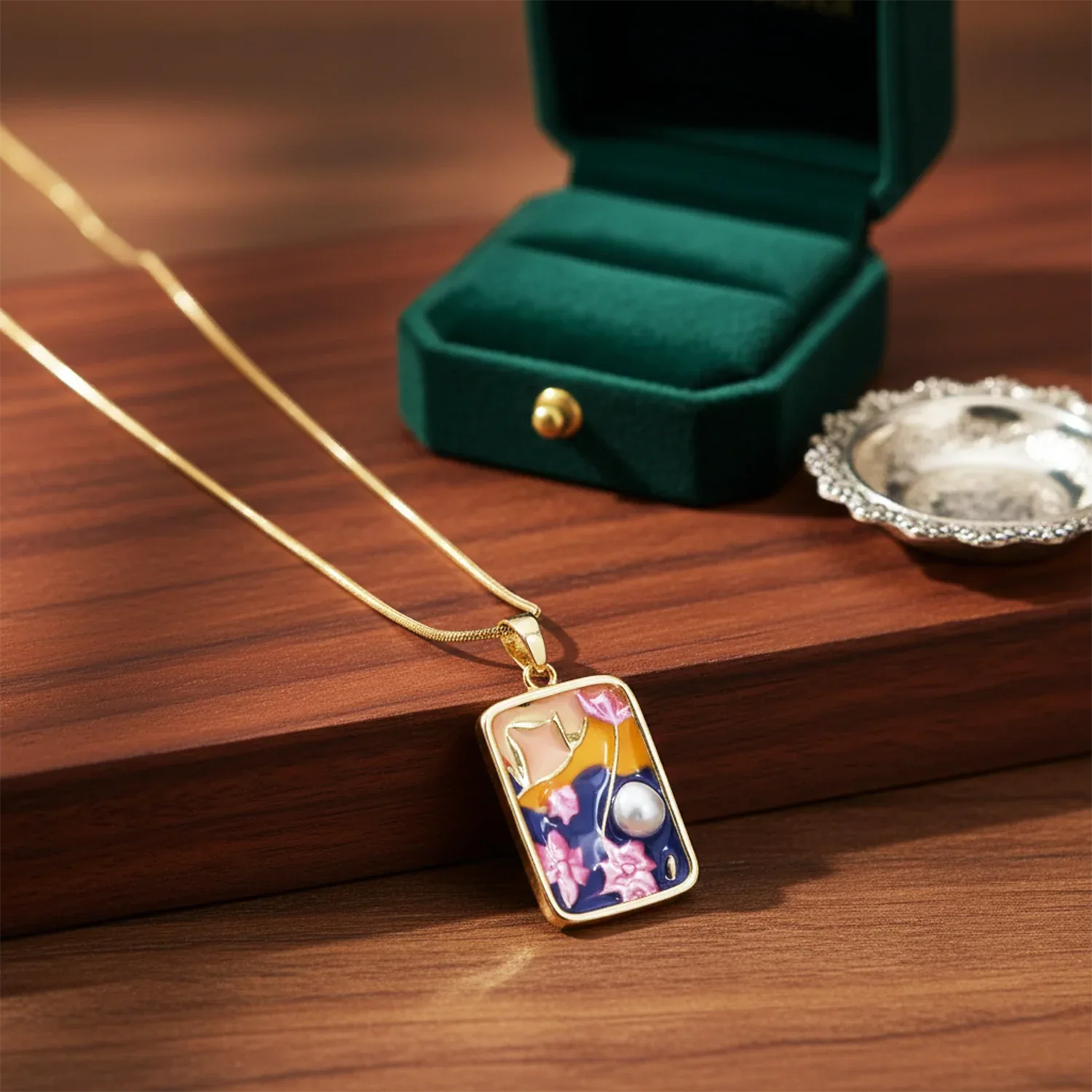 Gold necklace with a decorative pendant on a wooden surface with a green jewelry box in the background.