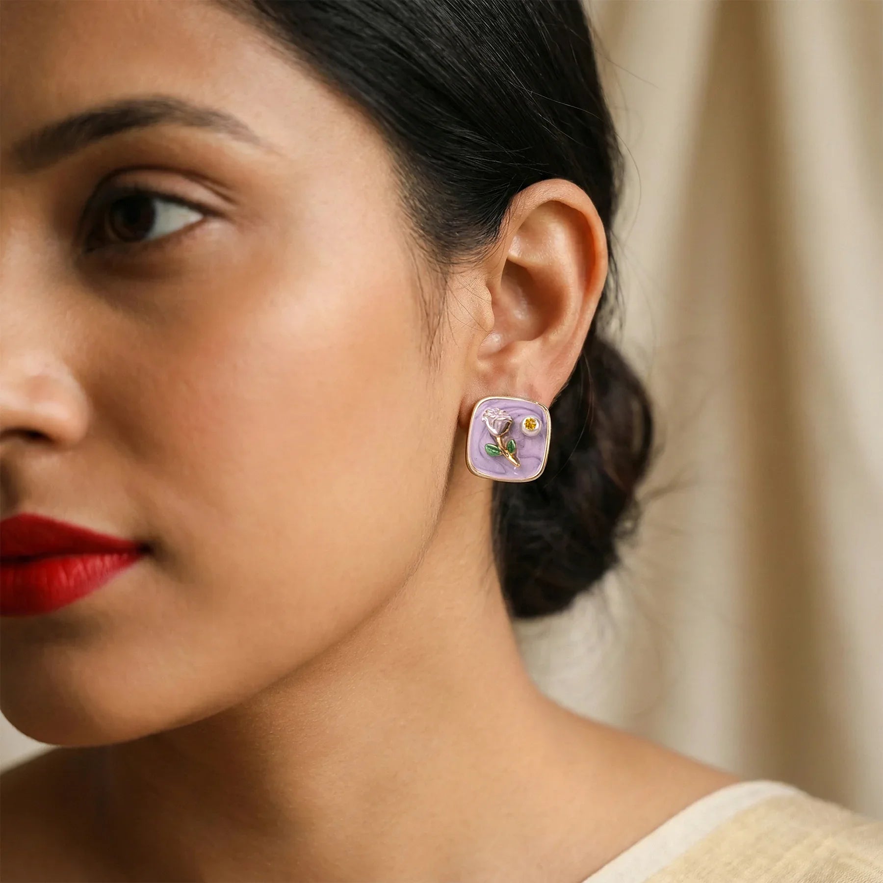 Close-up of a woman wearing a purple earring with floral design.
