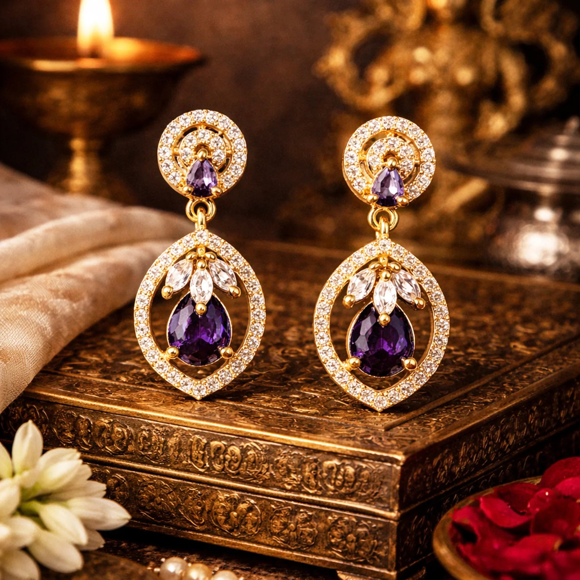 Pair of ornate earrings with purple stones on a decorative wooden box.