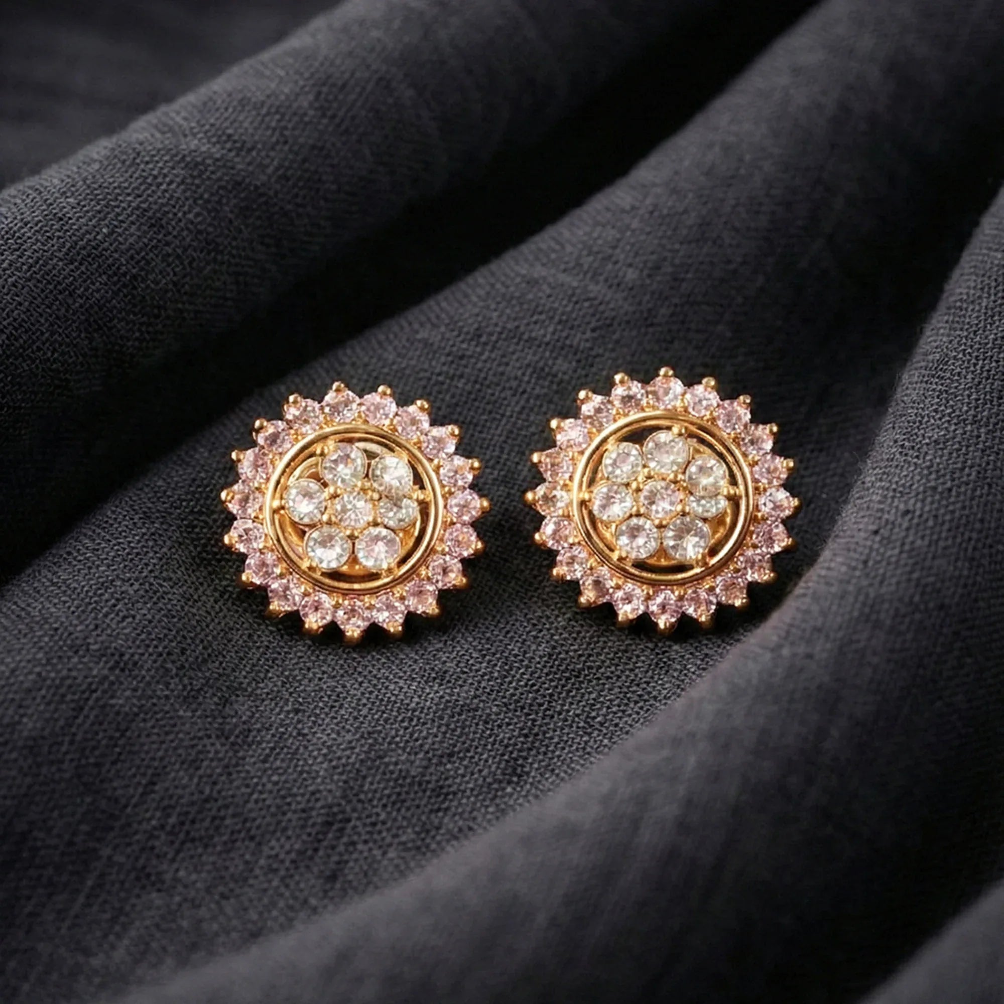 Gold and diamond earrings on a dark fabric background