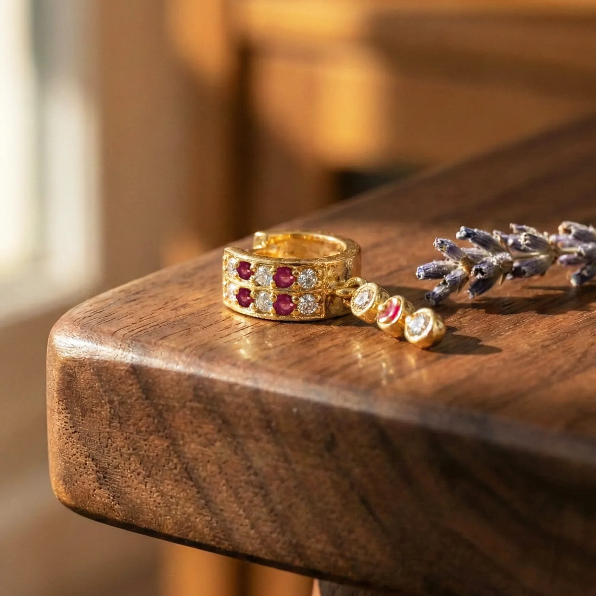 Gold ring with red gemstones and diamond accents on a wooden surface
