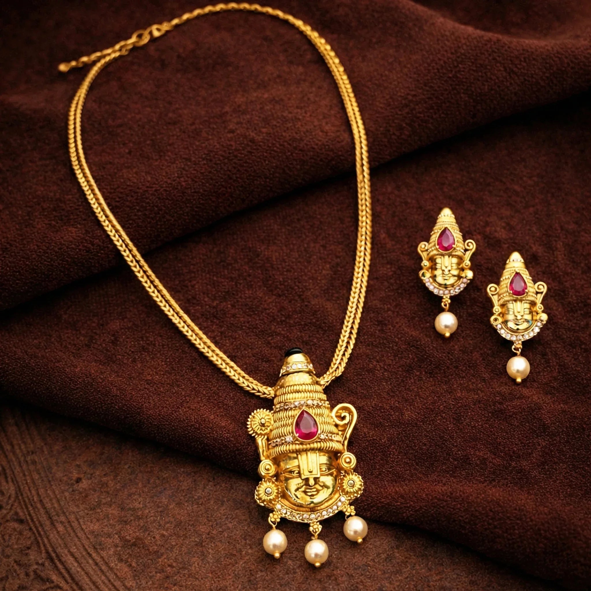 Gold necklace and earrings set on a brown fabric background