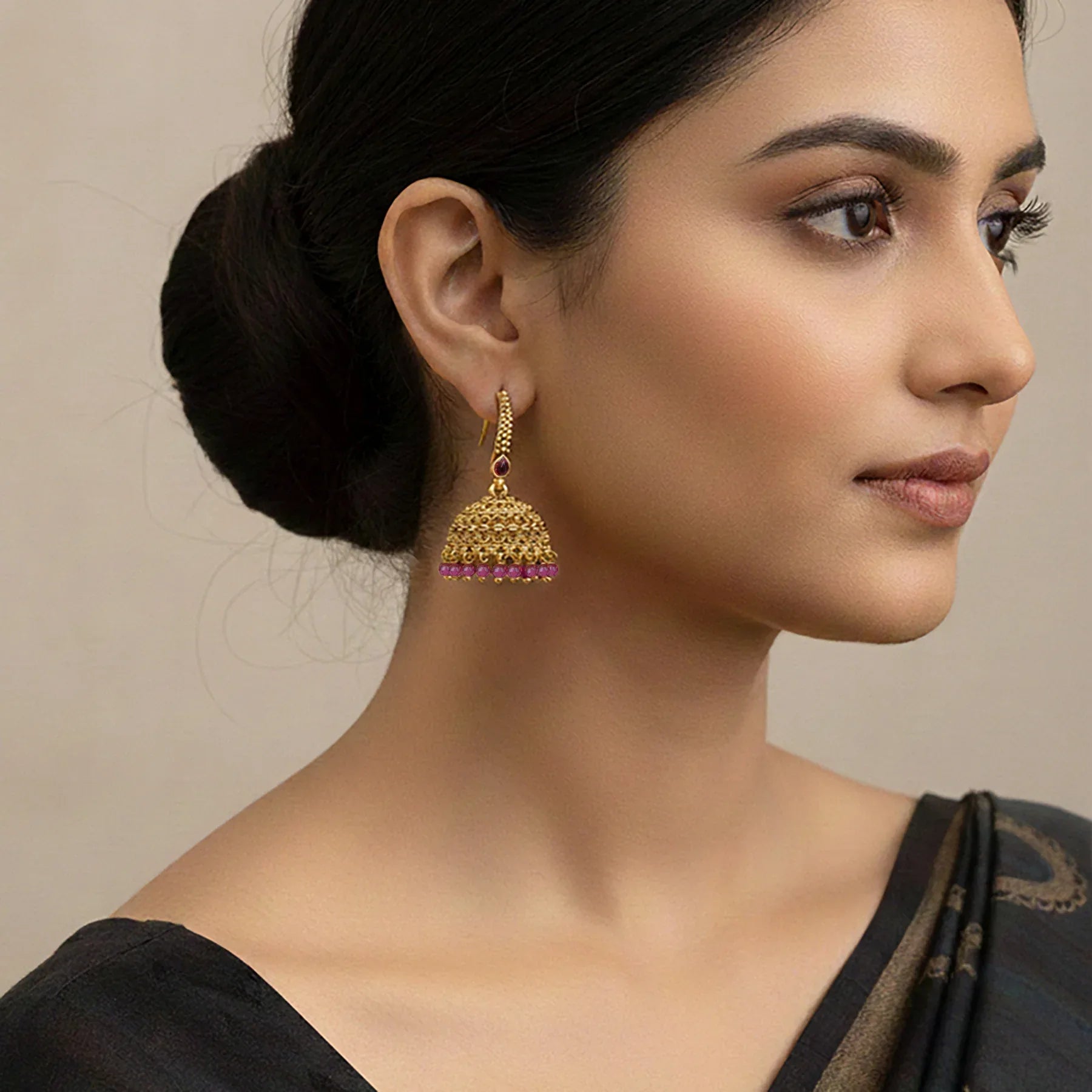 Woman wearing gold earrings with a neutral background