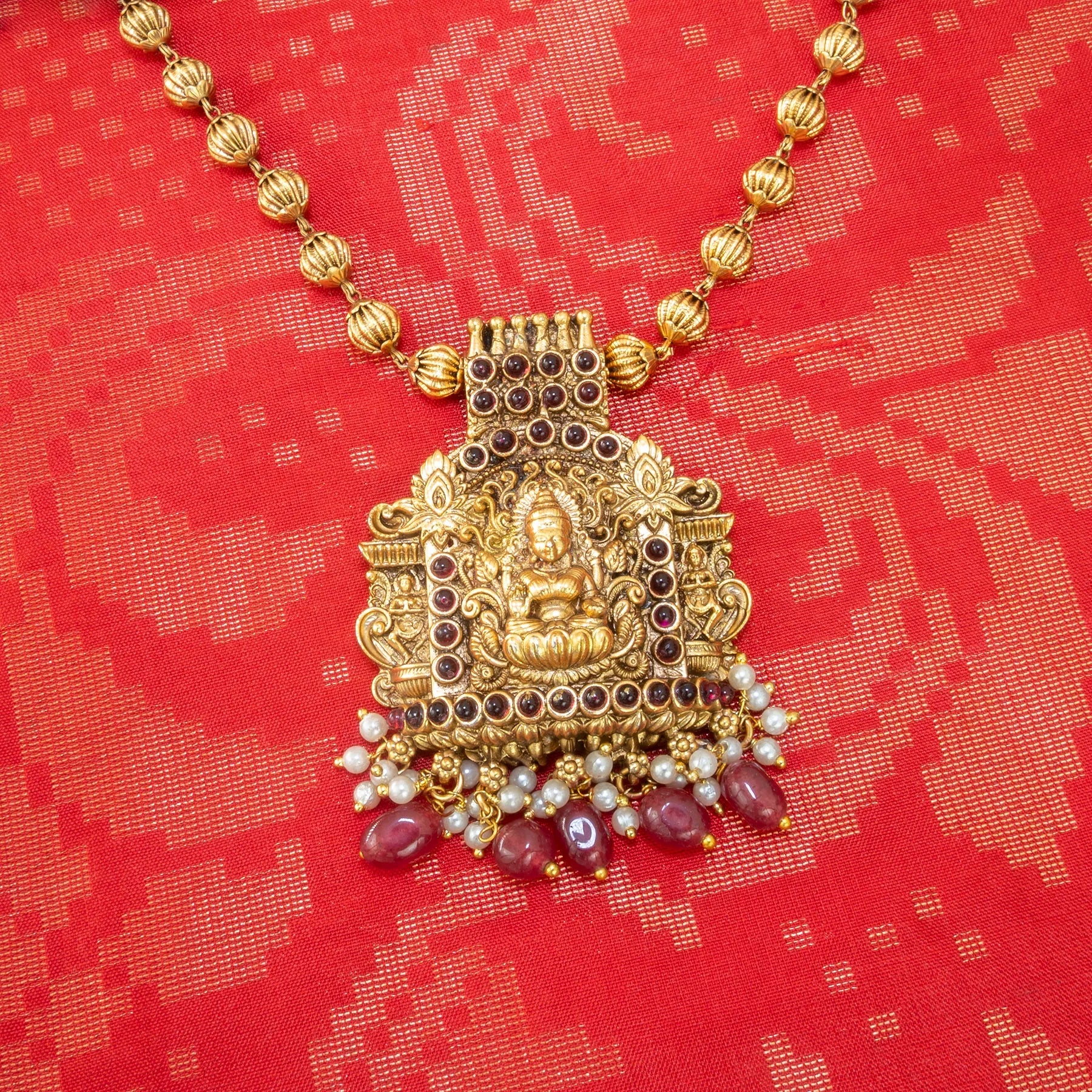 Gold necklace with a pendant on a red fabric background