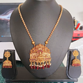 Gold necklace with red stones and matching earrings on a black mannequin bust.