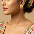 Close-up of a woman wearing gold earrings with a floral headpiece and traditional outfit.