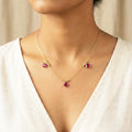 Necklace with pink gemstones worn by a person in a white top.