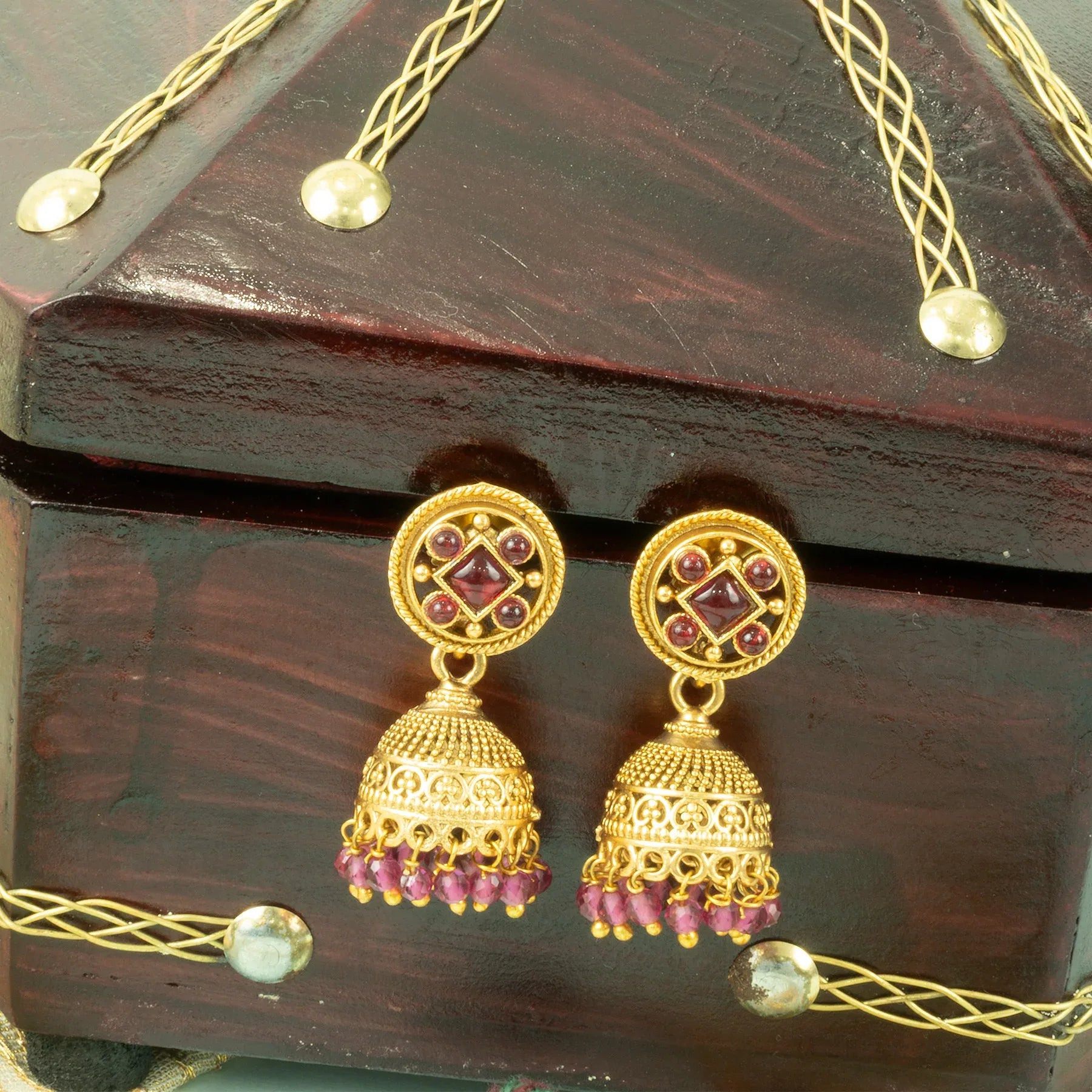 Gold and purple earrings on a wooden surface