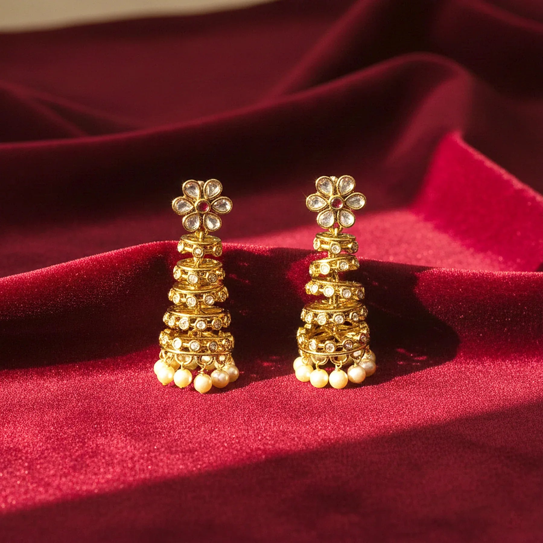 Pair of gold and pearl earrings on a red fabric background