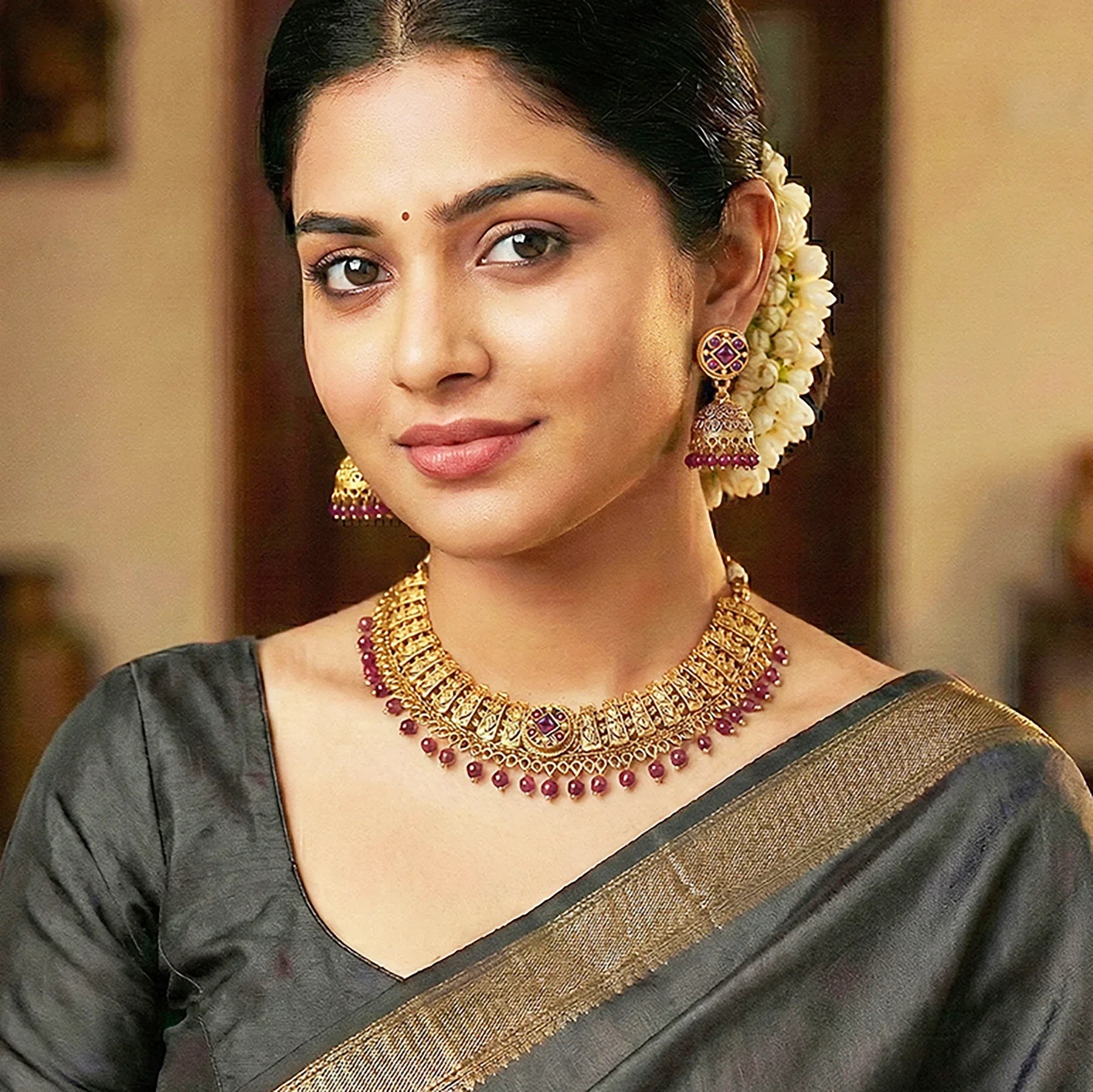 Woman wearing traditional jewelry and a saree with a blurred background