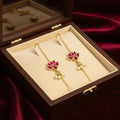 Gold earrings with red gemstones and pearl accents in a jewelry box.