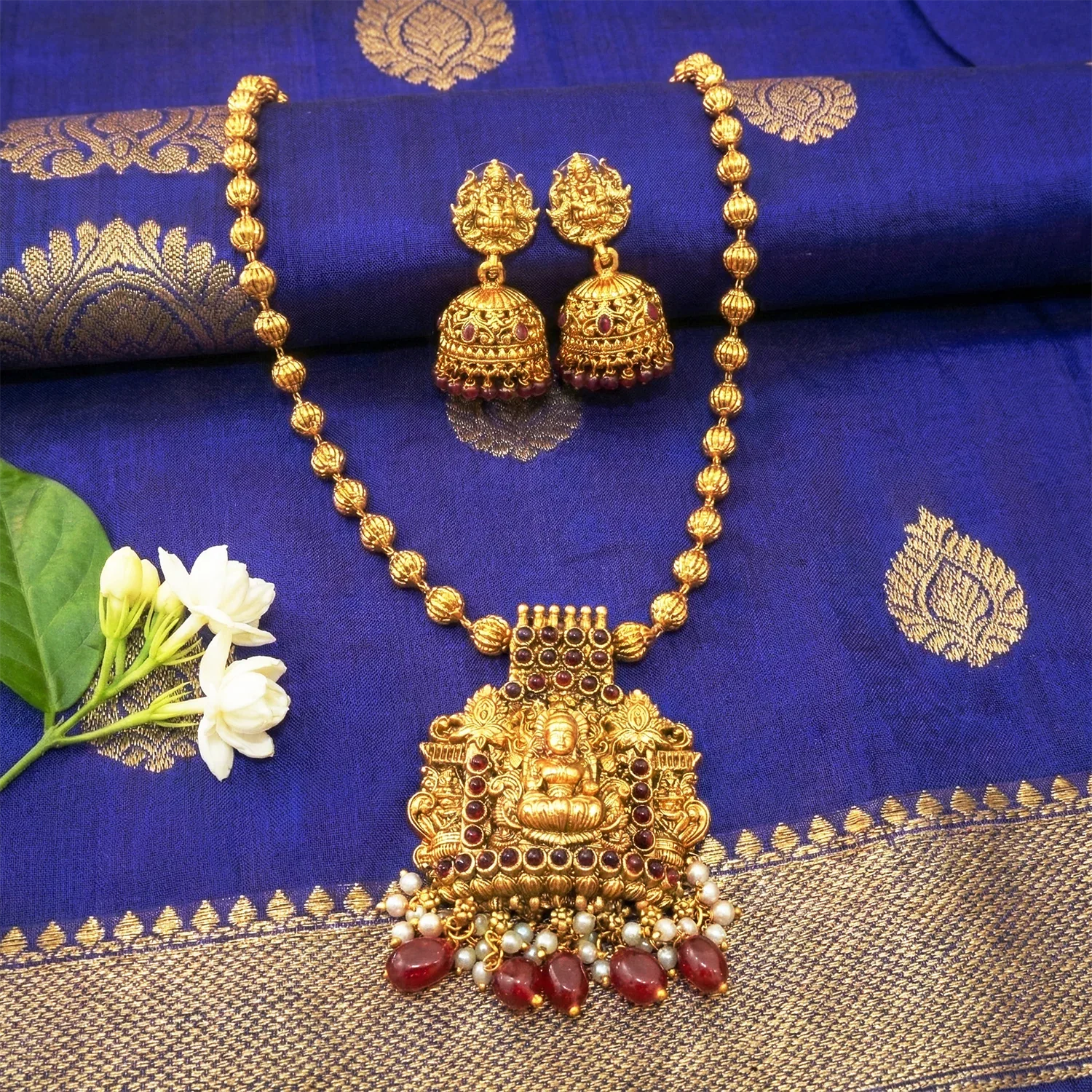Gold necklace and earrings on a blue fabric background
