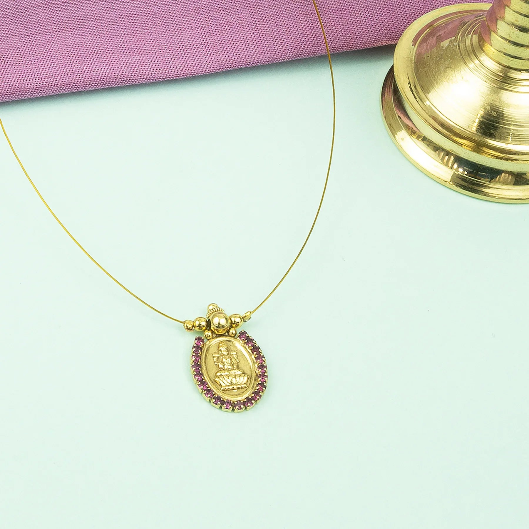 Gold necklace with a pendant on a light green background