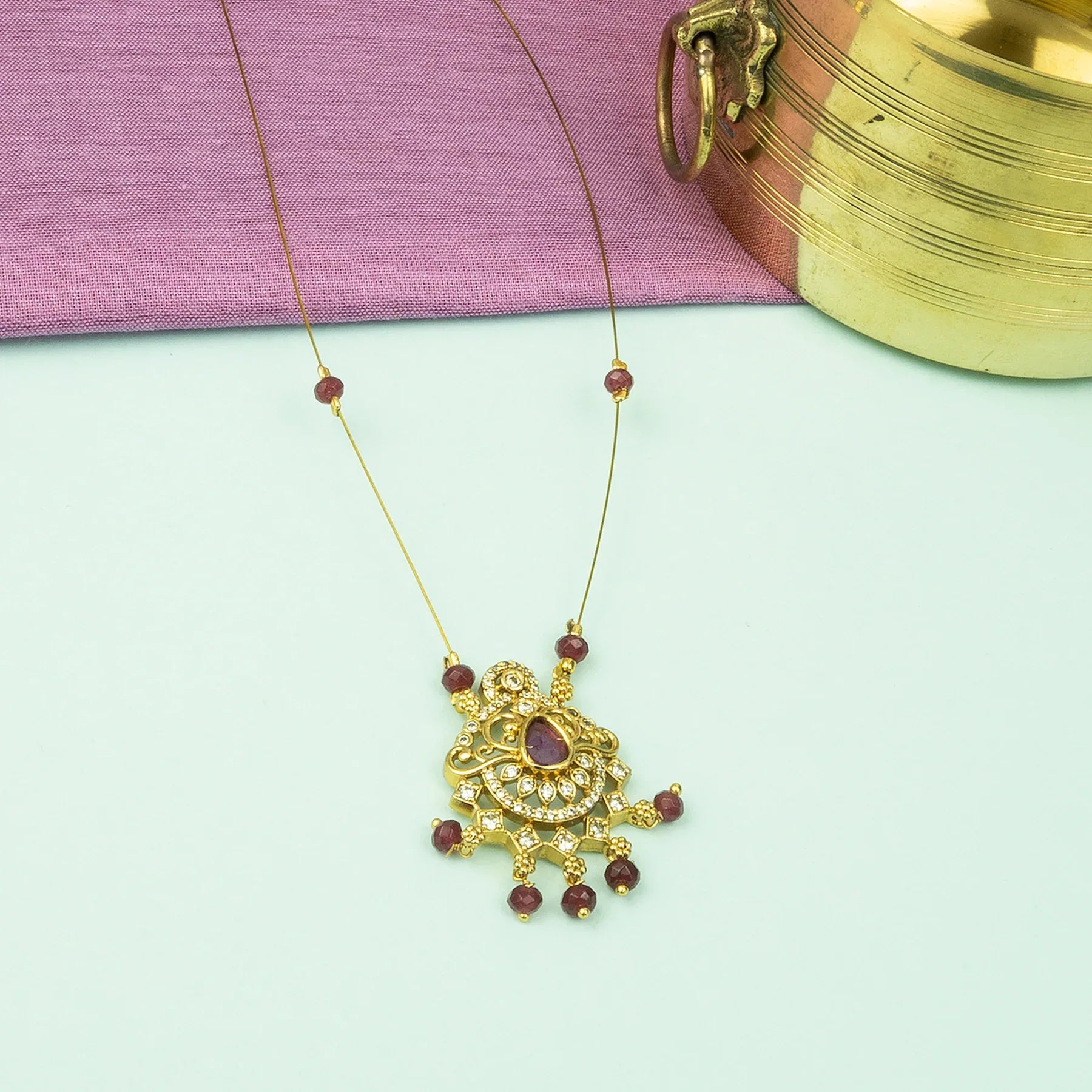 Gold necklace with a pendant on a light green background