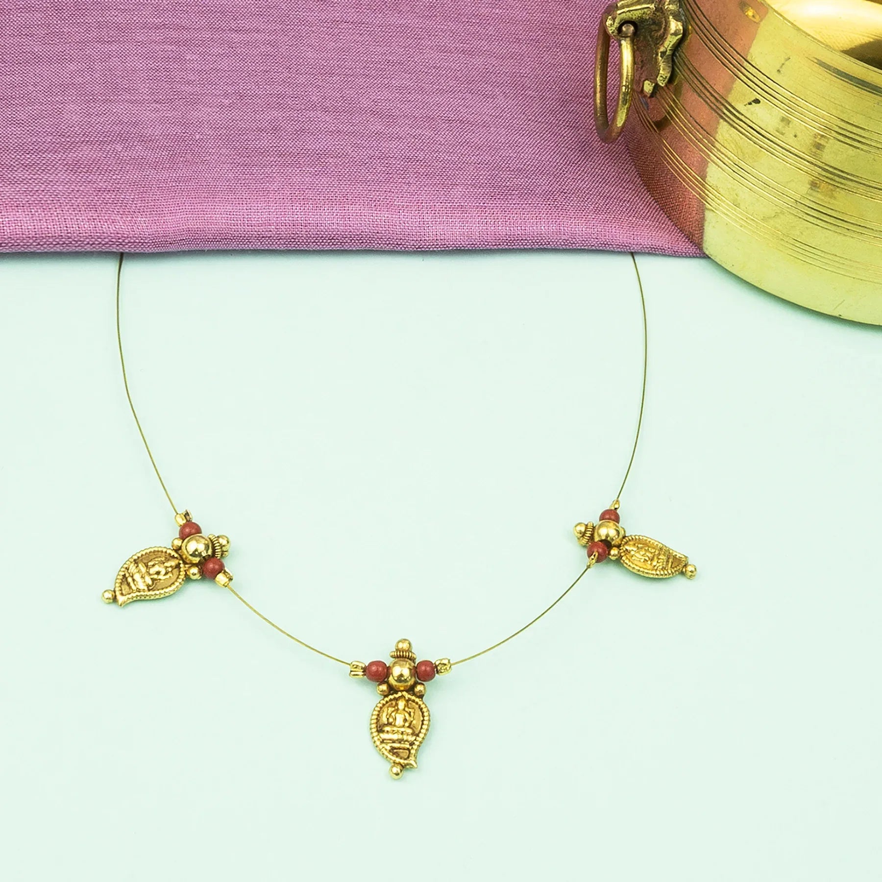 Gold necklace with red stones on a light green background