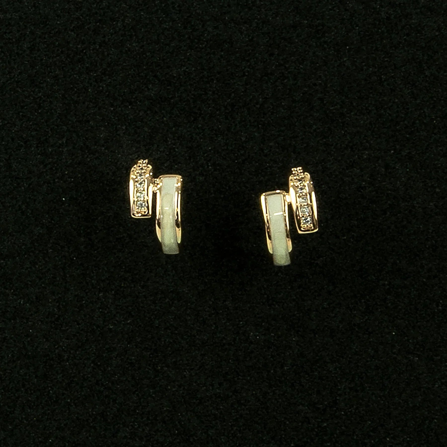 Pair of gold hoop earrings with green gemstones on a black background