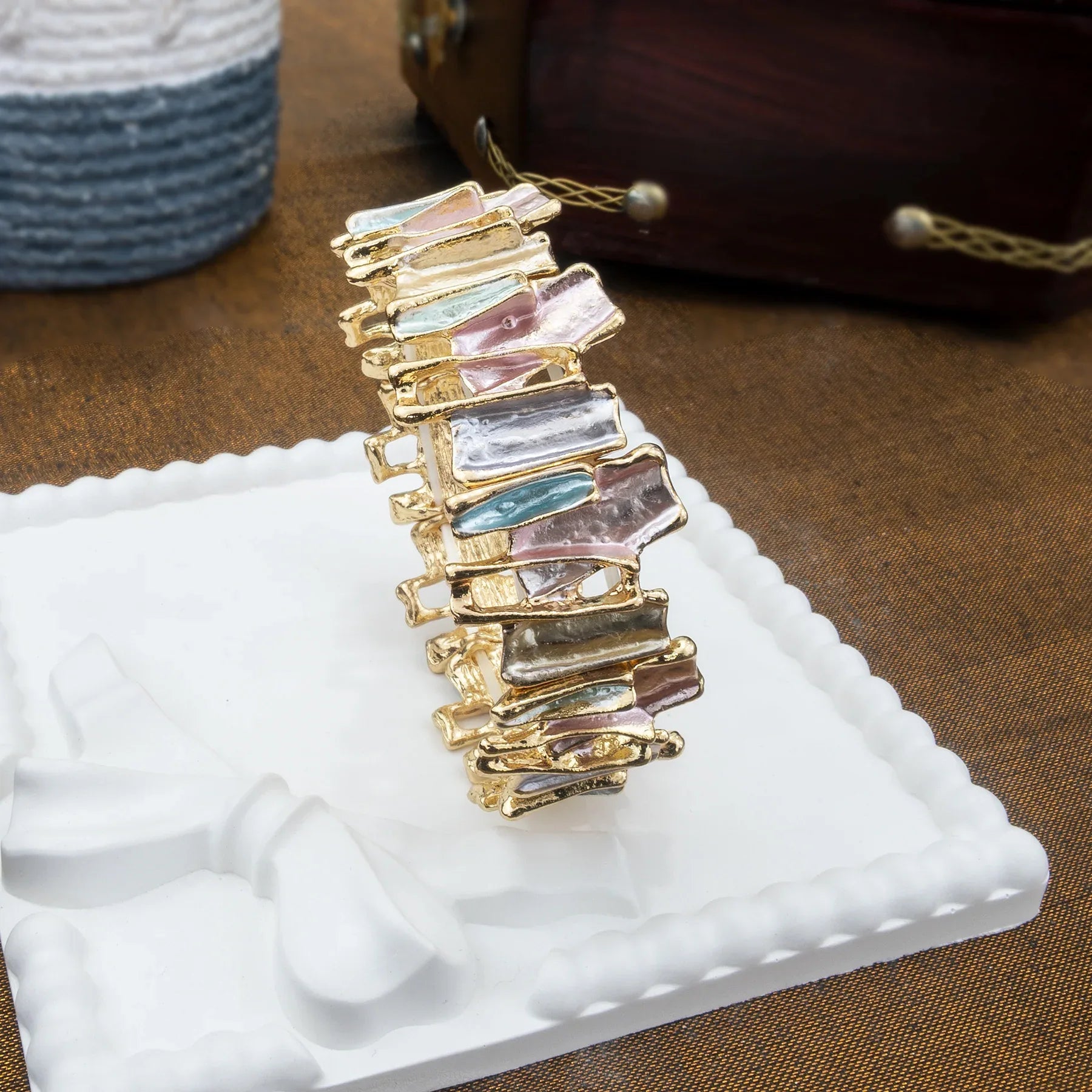 Multicolored gemstone hair clip on a white stand with a brown background