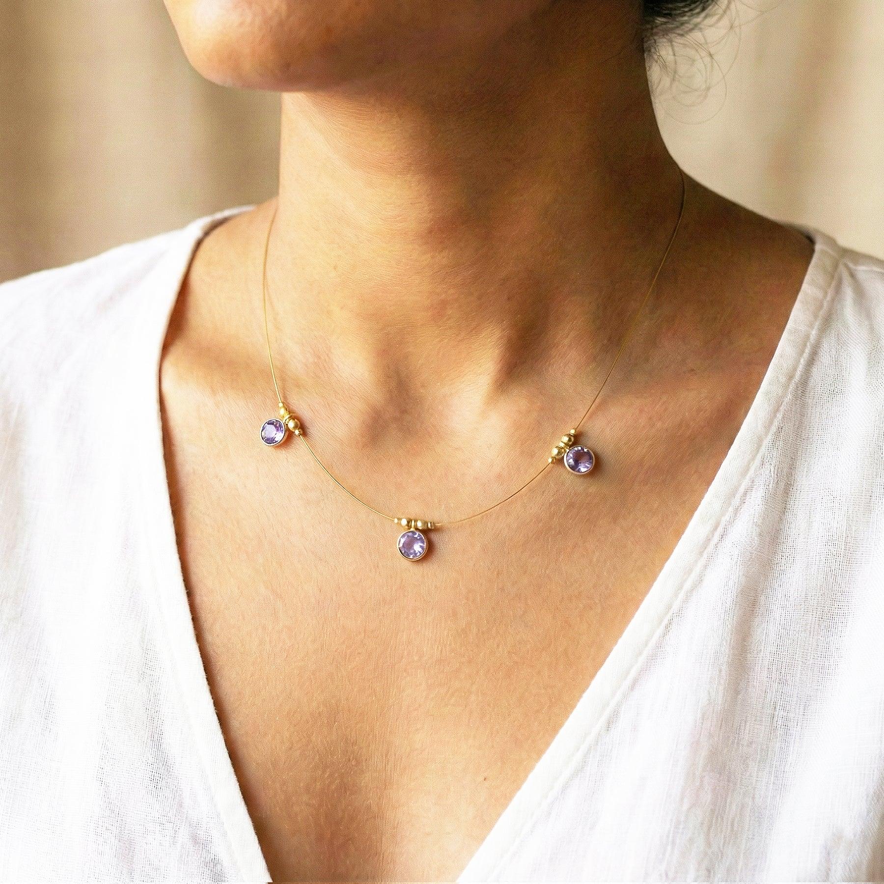 Necklace with purple gemstones worn by a person in a white top