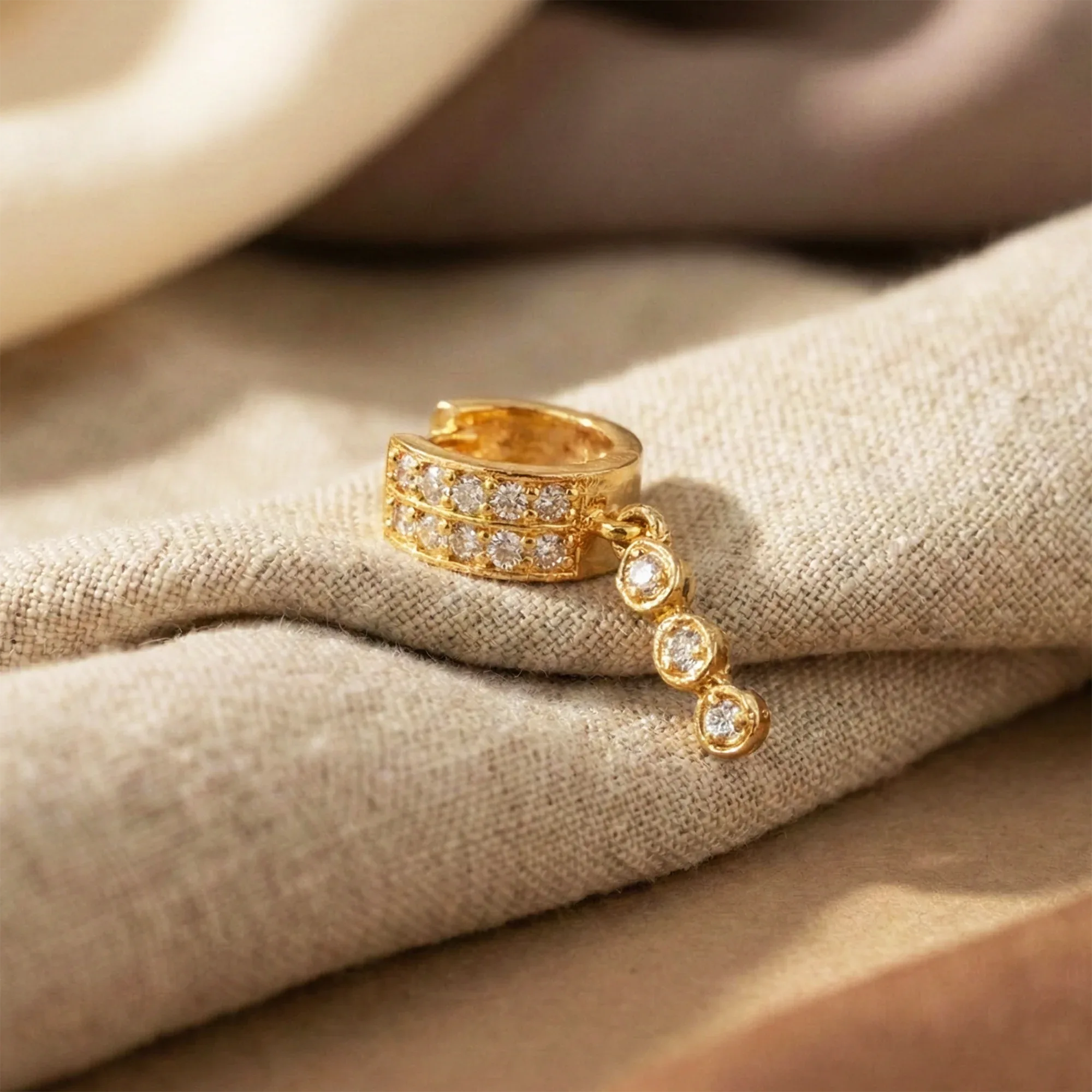 Gold ring with diamond accents on a beige fabric background