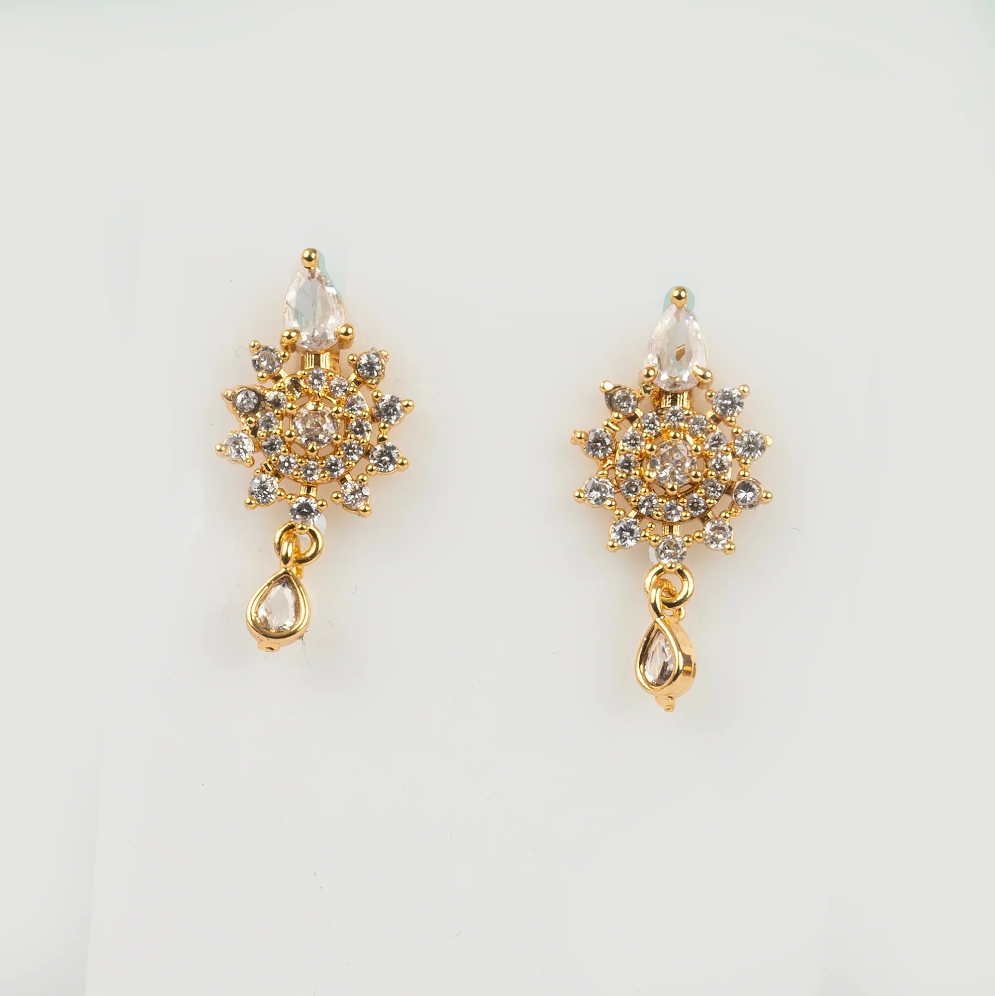 Gold earrings with gemstones on a light gray background