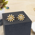Gold and crystal earrings on a black box with a decorative background