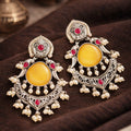 Ornate earrings with yellow stones and red gemstones on a dark surface