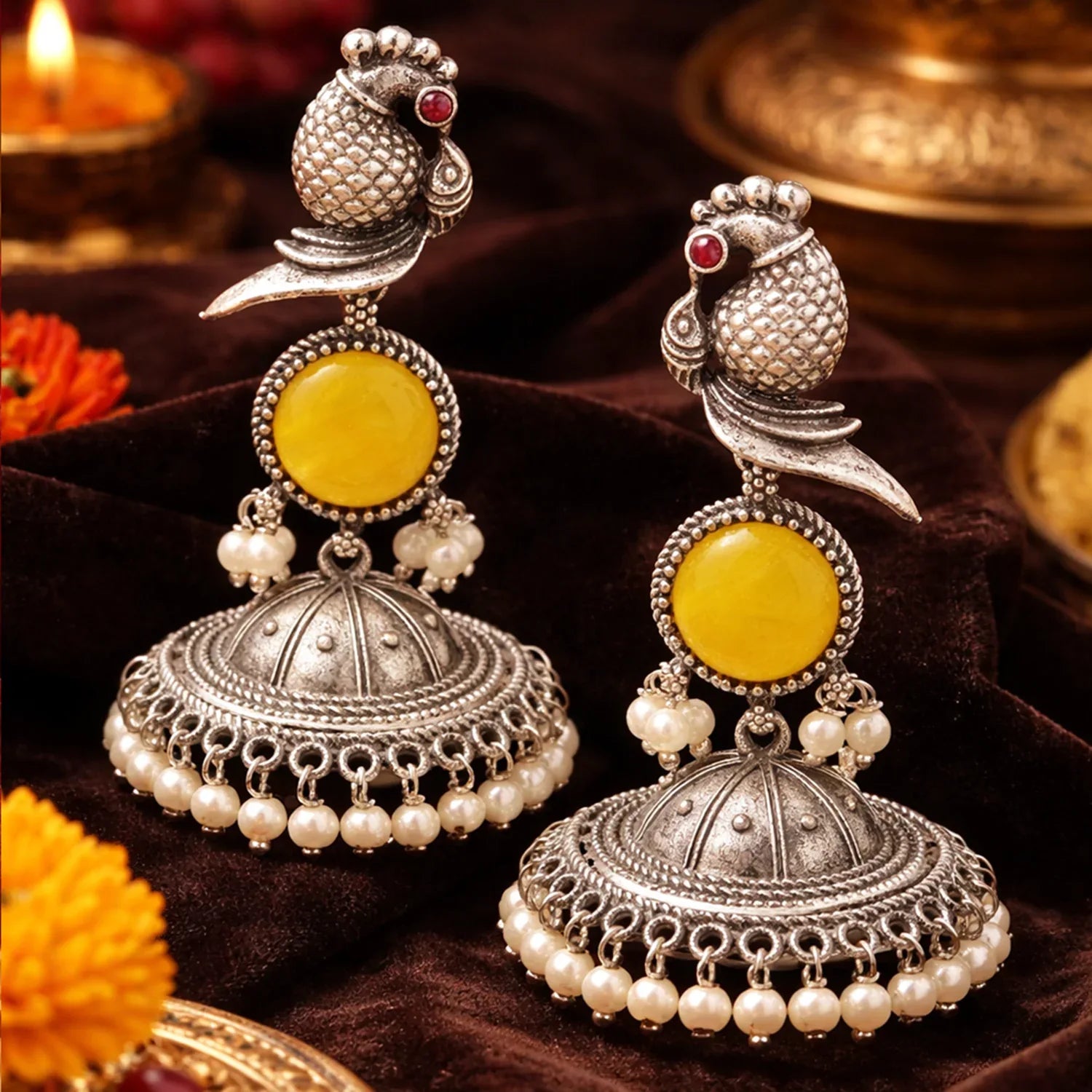 Pair of silver and yellow earrings with intricate designs on a dark background.