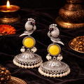 Pair of silver and yellow earrings with pearls on a dark background