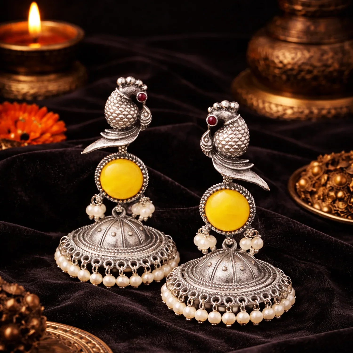Pair of silver and yellow earrings with pearls on a dark background